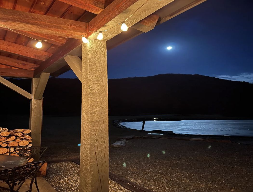 Cabin porch under string lights, moonlight over the pond